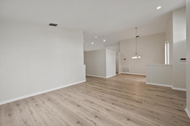 empty room featuring a notable chandelier and light wood-type flooring