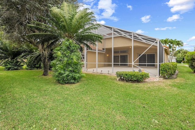 rear view of property with a yard, a lanai, and a patio