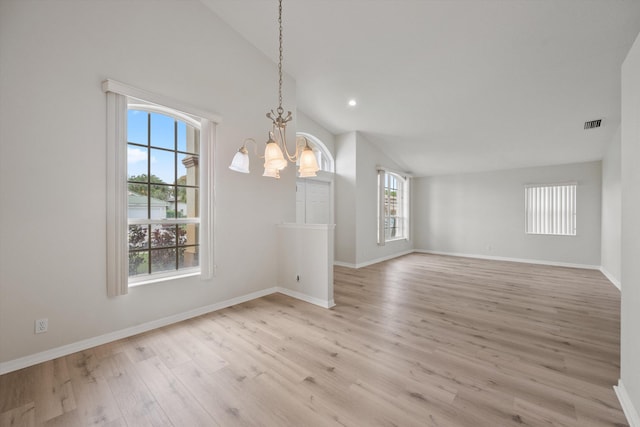 unfurnished dining area with lofted ceiling, a chandelier, and light hardwood / wood-style floors