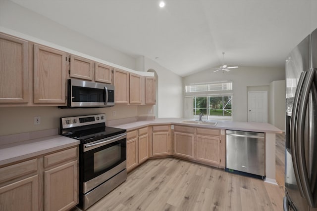 kitchen with vaulted ceiling, appliances with stainless steel finishes, light brown cabinetry, sink, and kitchen peninsula