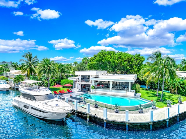 view of swimming pool featuring a lawn, a boat dock, a patio area, and a water view