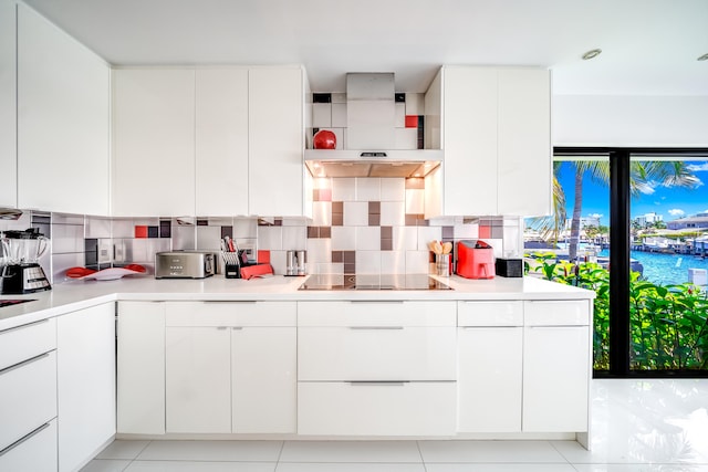 kitchen with black electric stovetop, decorative backsplash, and white cabinetry