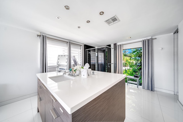 kitchen featuring sink, light tile patterned floors, and an island with sink