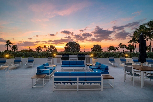 patio terrace at dusk featuring area for grilling and exterior kitchen