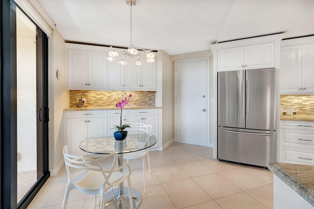 kitchen featuring stainless steel refrigerator, white cabinetry, tasteful backsplash, pendant lighting, and light tile patterned flooring