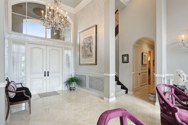 foyer entrance with a notable chandelier, crown molding, and a high ceiling