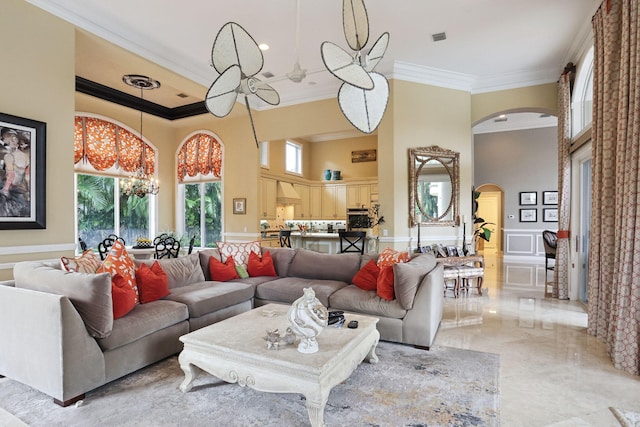 living room with crown molding, a towering ceiling, and a chandelier