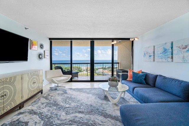 living room with a water view, light tile patterned floors, a textured ceiling, and a wall of windows