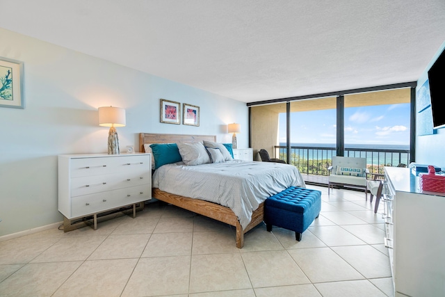 tiled bedroom with access to outside, expansive windows, and a textured ceiling