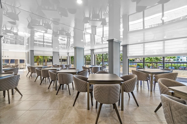 dining area featuring a towering ceiling, a healthy amount of sunlight, and light tile patterned floors