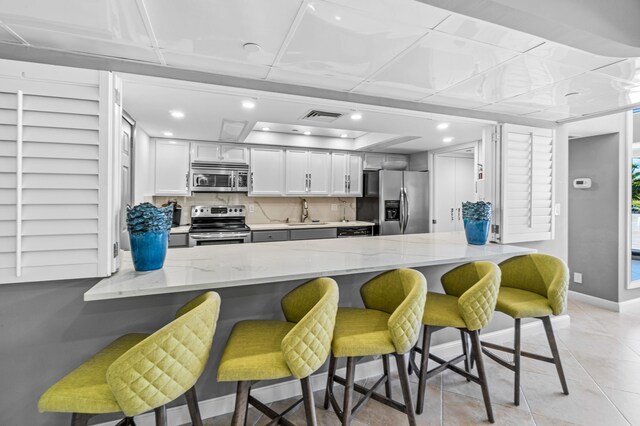 kitchen with stainless steel appliances, a breakfast bar, kitchen peninsula, and white cabinets