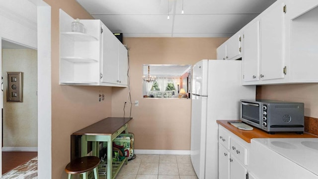 kitchen with white cabinets, white fridge, a notable chandelier, and light tile patterned flooring