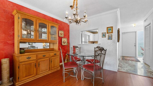 dining room with a textured ceiling, dark hardwood / wood-style floors, crown molding, and an inviting chandelier