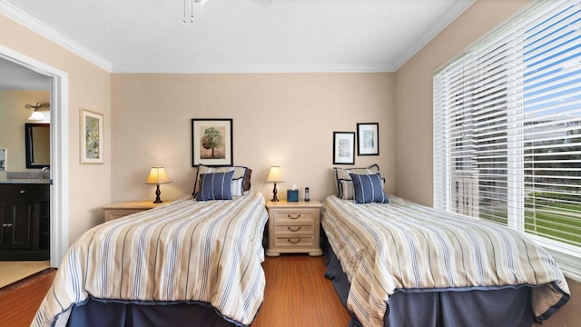 bedroom with connected bathroom, crown molding, hardwood / wood-style floors, and multiple windows