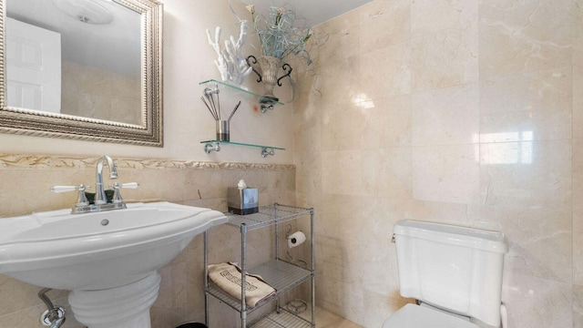 bathroom featuring sink, tile walls, and toilet