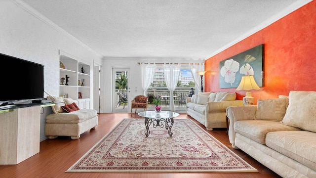 living room featuring built in features, hardwood / wood-style floors, a textured ceiling, and ornamental molding