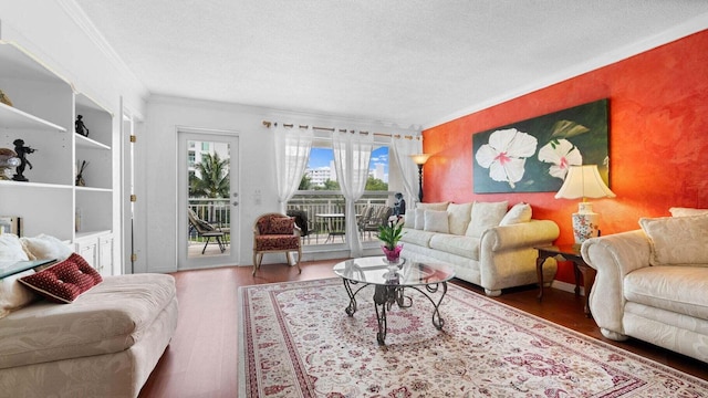 living room featuring wood-type flooring, a textured ceiling, and ornamental molding