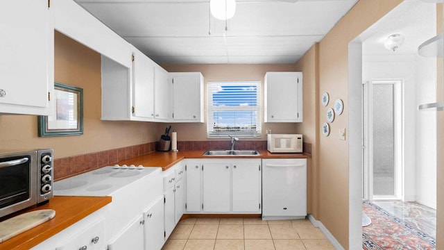 kitchen with white cabinets, white appliances, light tile patterned flooring, and sink