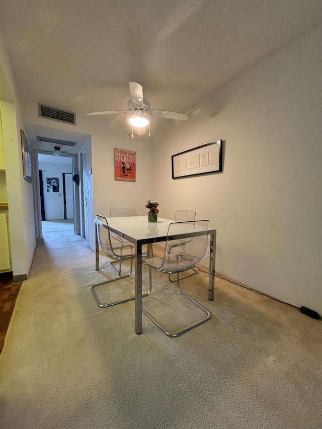 dining area featuring carpet flooring, a textured ceiling, and ceiling fan