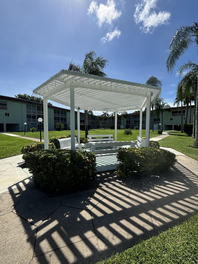 view of community featuring a pergola and a lawn