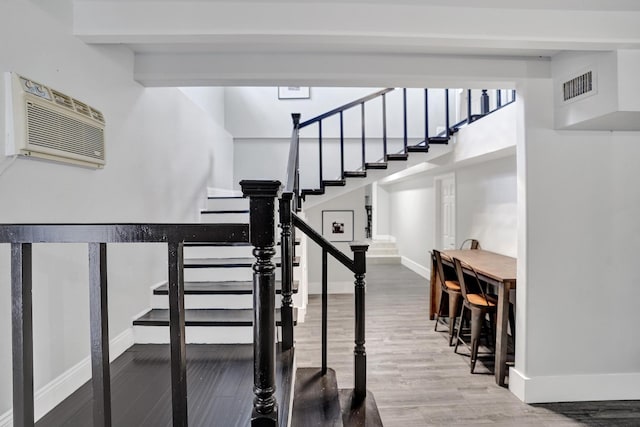 staircase with a wall unit AC and wood-type flooring