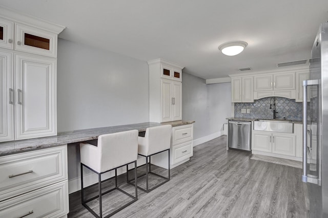 kitchen featuring backsplash, white cabinets, light hardwood / wood-style flooring, stone countertops, and stainless steel appliances