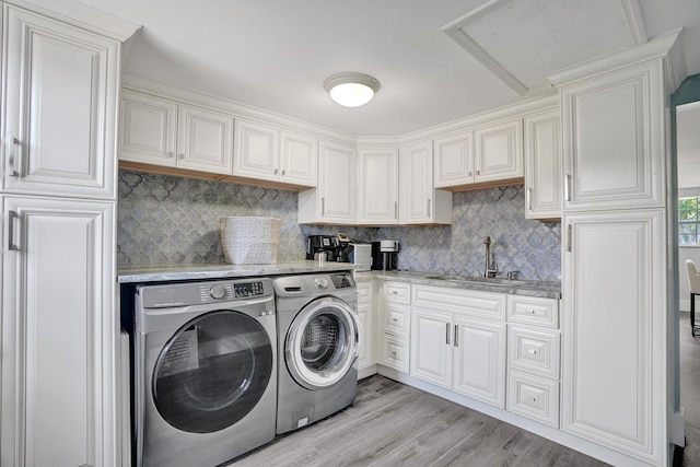 washroom featuring washing machine and dryer, light hardwood / wood-style flooring, and sink