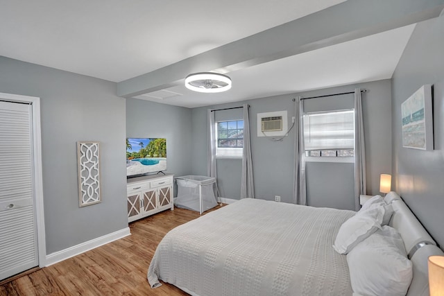 bedroom with light hardwood / wood-style floors and a wall mounted air conditioner