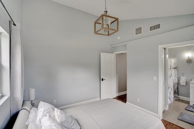 tiled bedroom with a chandelier, ensuite bath, and lofted ceiling