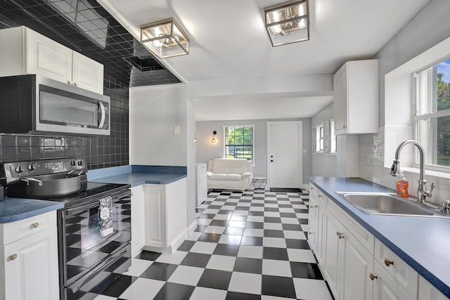 kitchen featuring white cabinets, sink, and black range with electric cooktop