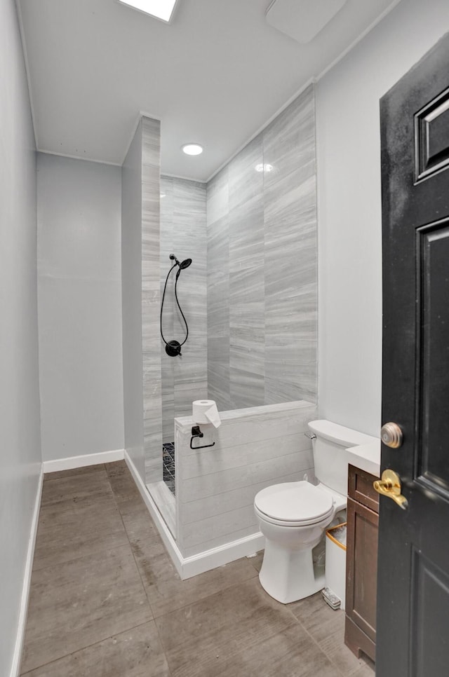 bathroom with toilet, tile patterned flooring, and tiled shower