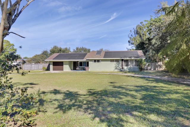 view of front of house featuring a front yard, solar panels, and a garage