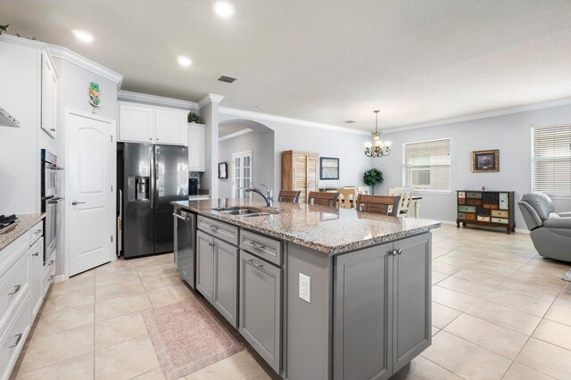 kitchen with light stone counters, a breakfast bar, stainless steel appliances, a center island with sink, and white cabinetry