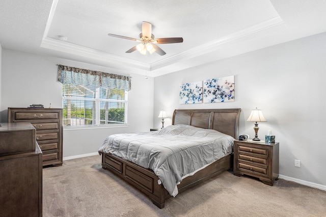 bedroom featuring ceiling fan, ornamental molding, light carpet, and a tray ceiling