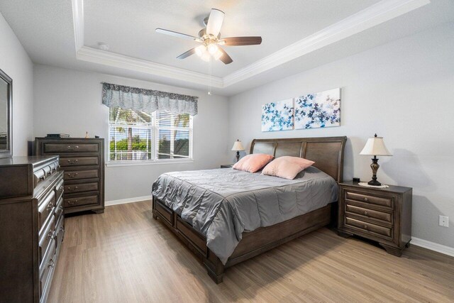 bedroom featuring wood finished floors, a raised ceiling, visible vents, and baseboards