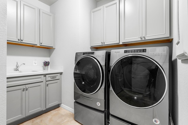 laundry area featuring washer and dryer, light tile patterned flooring, cabinets, and sink