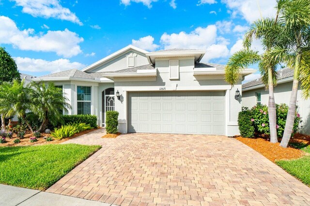 view of front of house with a garage, decorative driveway, a front lawn, and stucco siding