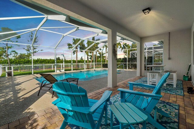 view of swimming pool featuring glass enclosure, fence, a fenced in pool, and a patio