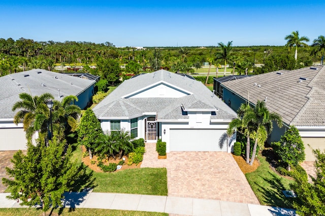 exterior space with a shingled roof, decorative driveway, an attached garage, and stucco siding