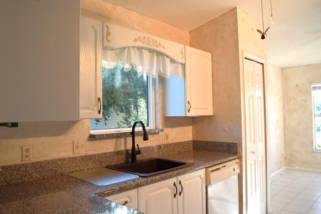 kitchen with white dishwasher, white cabinetry, and sink