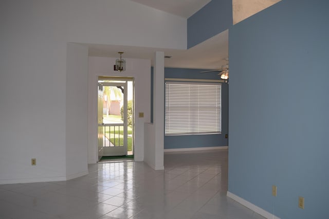 foyer with ceiling fan with notable chandelier and light tile patterned floors