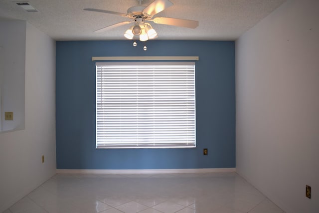 tiled spare room with a textured ceiling and ceiling fan