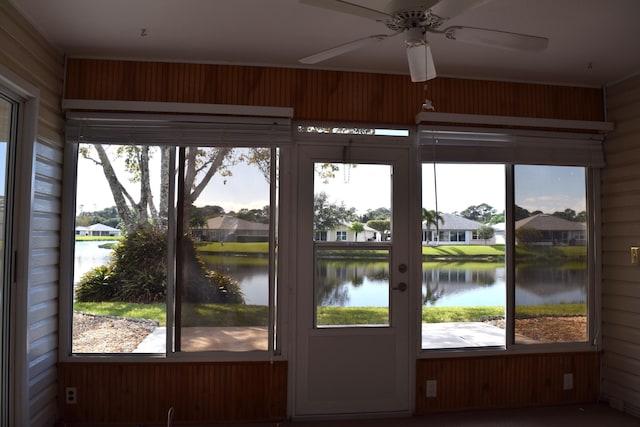 doorway to outside featuring ceiling fan, wood walls, and a water view