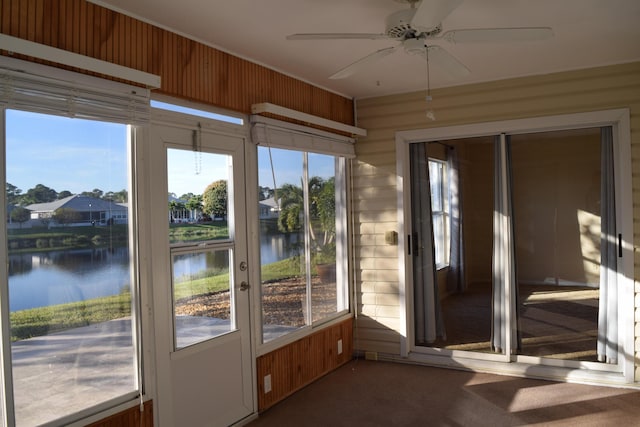 unfurnished sunroom with ceiling fan, a healthy amount of sunlight, and a water view