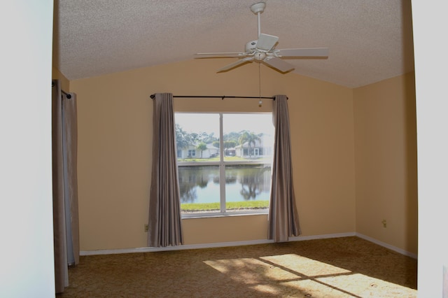 carpeted empty room featuring a textured ceiling, a water view, ceiling fan, and lofted ceiling