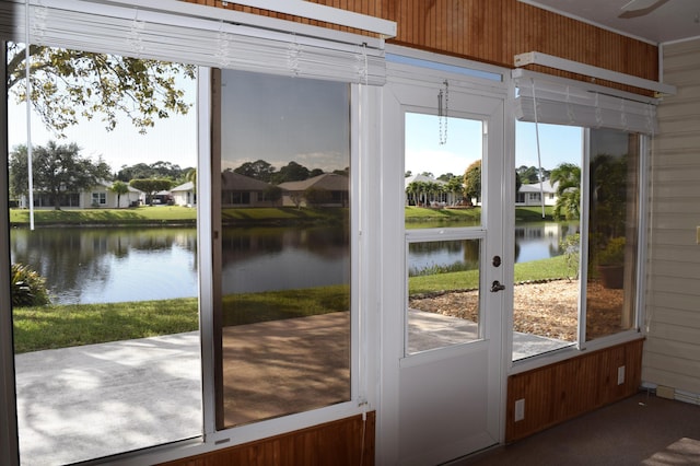 doorway with a water view and wood walls