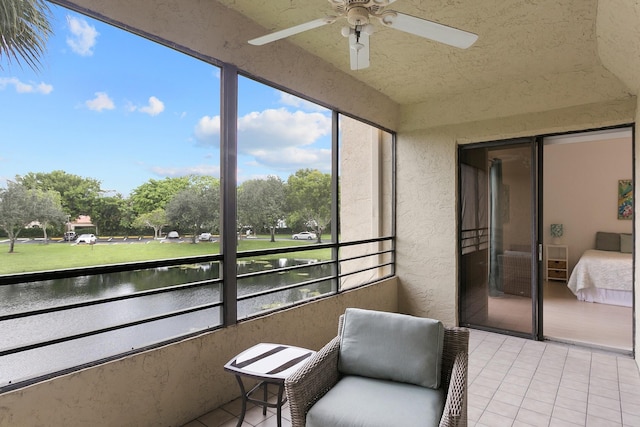 sunroom featuring ceiling fan and a water view