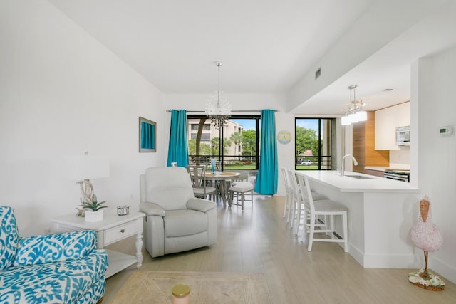 dining room with light hardwood / wood-style flooring, sink, and an inviting chandelier