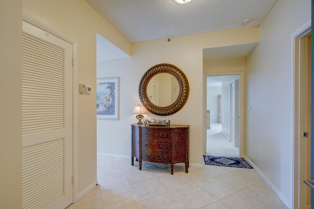 corridor with a textured ceiling and light tile patterned flooring