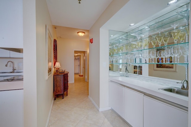 bar featuring white cabinets, light tile patterned floors, and sink